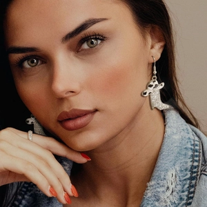 Close-up of western cowgirl boot earrings with crystal pavé and cow print accents