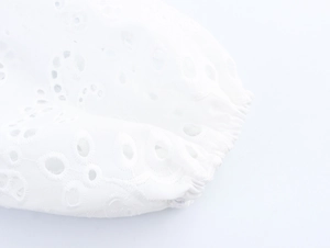Detail of white top sleeve featuring delicate hollow embroidery and elastic cuff