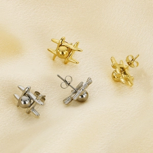 Detailed top view of 14k gold and silver airplane stud earrings on silk fabric