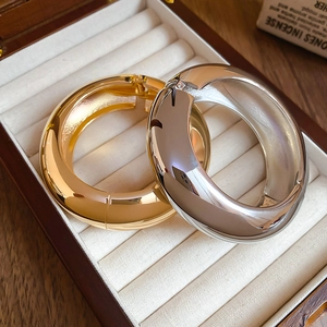 Chic wide gold and silver polished metal open bangles in a wood jewelry box display