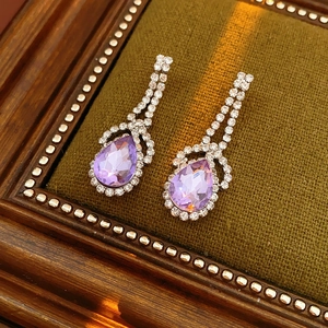 Dettaglio macro di orecchini vintage a goccia con cristalli viola e strass luccicanti
