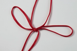 Close-up of red satin dress shoulder straps with elegant tie-knot detail and silky finish