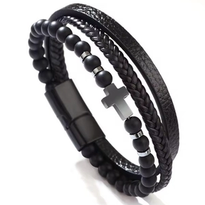 Bracelet multicouche en cuir noir avec perles mates et pendentif croix sur fond blanc