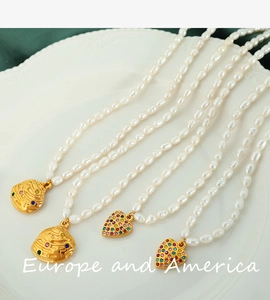 Detail of freshwater pearl necklace with gold heart and shell pendants with colorful gems