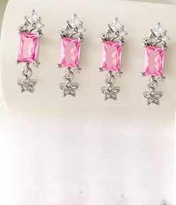 Macro detail of silver geometric ear stud featuring pink zircon and star pendant decoration