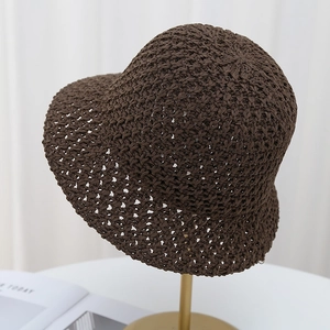 Brown woven hollow bucket hat for women with breathable sun protection on a metal stand