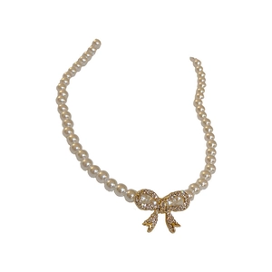 Elegant French vintage pearl headband with a sparkling golden rhinestone bow on white background