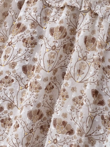 Close-up of tan floral print and white 3D embroidery on breathable V-neck shirt fabric
