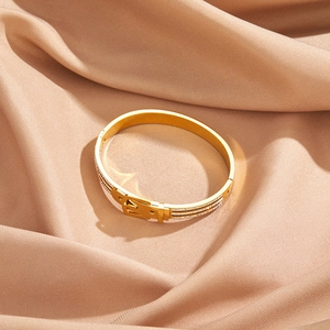 Macro detail of gold-plated belt buckle bracelet with pavé-set crystals on champagne satin