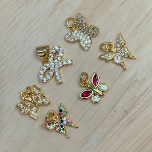Set of six gold butterfly and bow pendants with multicolored zircon crystals on wood