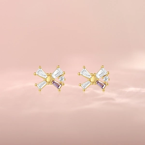 Close-up of S925 silver bow stud earrings featuring gold plating and purple zircons