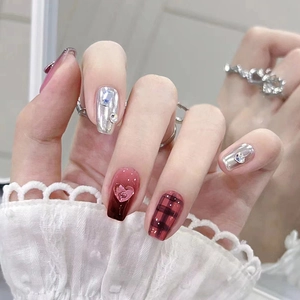 Unghie finte sfumate nero-rosso con accenti metallici argento e strass a cuore rosa.