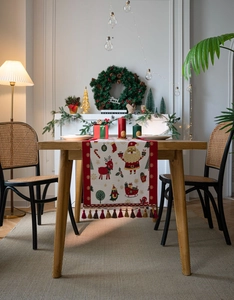 Macro detail of Christmas table runner with reindeer motifs and decorative red tassels