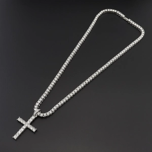 Silver tennis chain necklace with a large cross pendant featuring shiny clear stones on black