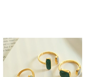 Detail view of three vintage gold rings with green rectangular stones on text background