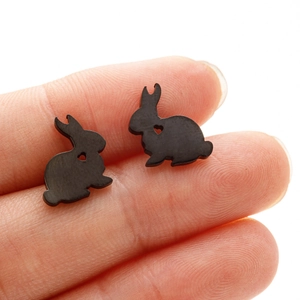 Minimalist black stainless steel bunny stud earrings with heart cutout held by fingers
