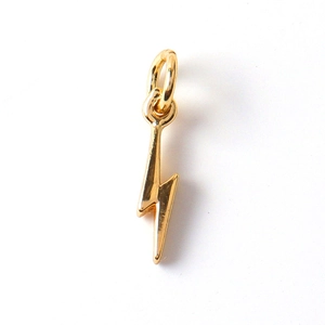 Close-up of a small gold-plated lightning bolt pendant with zircon for DIY jewelry