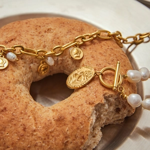 Detailed macro of vintage 18K gold coin pendant and freshwater pearl chain bracelet