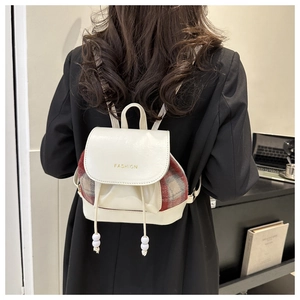 Detail eines Vintage-Karomusters des Mini-Rucksacks mit Kordelzug und Goldaufschrift