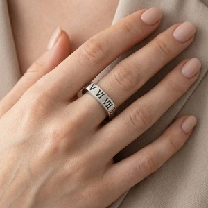 Détail d'une bague en acier inoxydable argenté avec chiffres romains gravés sur le doigt