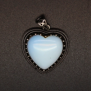 Macro detail of a heart-shaped moonstone pendant set in a textured silver metal frame