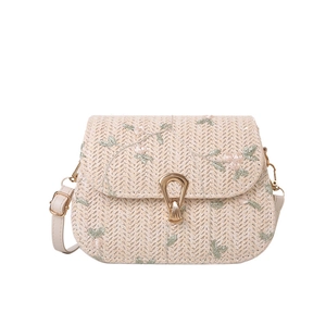 Straw crossbody bag with floral embroidery and gold hardware on white background
