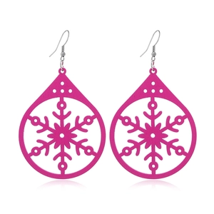 Detail of pink teardrop wooden earrings with delicate snowflake cutout patterns