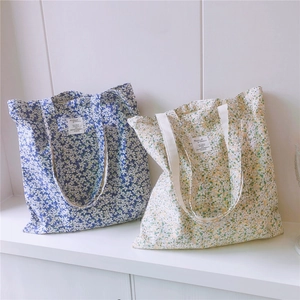 Close-up of blue and beige floral cotton tote bags with minimalist textile labels