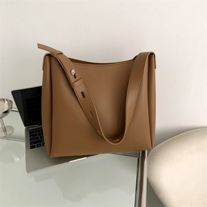 Minimalist brown faux leather tote bag next to a laptop on a glass desk for office use