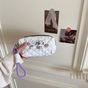 Detailed shot of white quilted stationery bag with cartoon print and purple woven handle