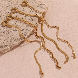 Detailed macro view of gold plated paperclip and snake chain bracelets on stone