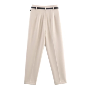 Detail view of high-waisted beige trousers with a slim black leather belt and crisp pleats