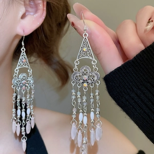 Detail of ethnic tassel earrings featuring hollow triangles and pink waterdrop charms