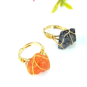 Macro shot of handmade wire wrapped rings featuring raw orange agate and black stone beads