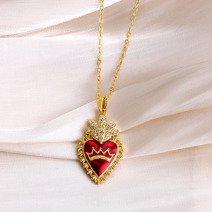 Macro detail of red heart pendant with golden crown relief and sparkling zirconia inlay
