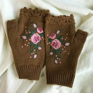 Close-up of brown knit fingerless gloves with delicate pink rose floral embroidery