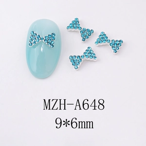 Détail de bijoux d'ongles nœud bleu clair 9x6mm avec base métallique et strass brillants