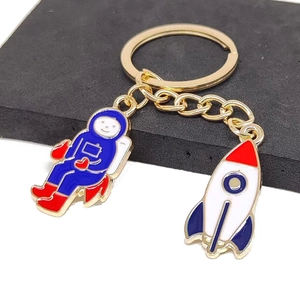 Close-up of golden enamel keychain with colorful astronaut and rocket pendants