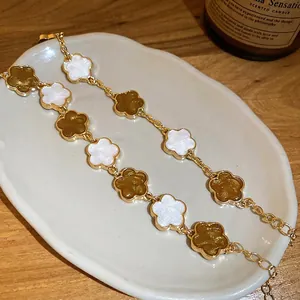 Bracelet vintage français doré avec fleurs émaillées blanches et ambre sur une assiette blanche
