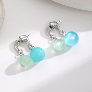 Handmade raffia flower earrings with light green and sky blue beads on a white background