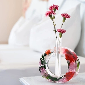 Détail du vase rond en résine époxy avec fleurs séchées intégrées et tube en verre