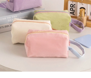 Dettaglio di trousse in velluto a coste in rosa, beige, verde e viola con cerniera e manico