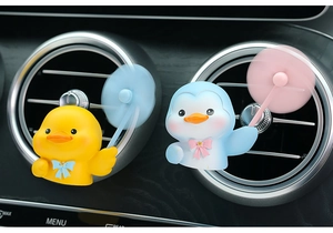 Close-up of cute cartoon duck and penguin car air vent air fresheners with propellers