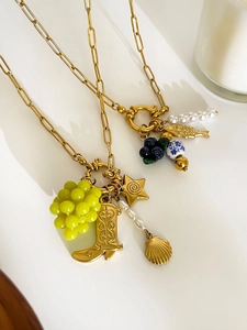 Detail of 18K gold necklaces featuring resin grapes and blue berries with pearl charms