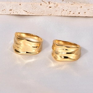 Artistic gold chunky wave rings with irregular lava texture in a minimalist setting
