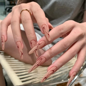 Lange stiletto kunstnagels in mat nude met rood marmerpatroon in gotische stijl