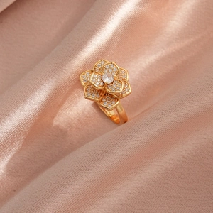 Bague fleur rotative élégante en or avec zircons brillants sur fond de soie rose doux