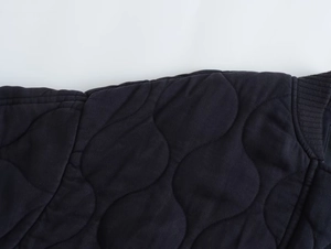 Détail de la veste matelassée bleu foncé avec piqûres ondulées et poignets côtelés