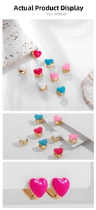 Macro detail of colorful heart enamel earrings with gold-plated finish on stone pedestals