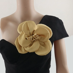 Detailed close-up of a large 3D golden satin rose brooch on a black formal dress
